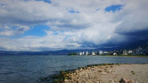 A beautiful scenery from the seashore with the blue sea and coastal city under the cloudy blue sky