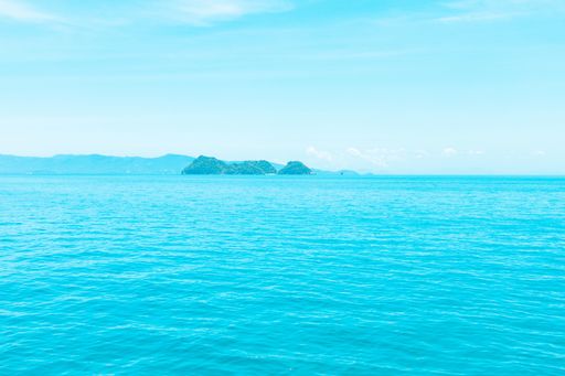 A beautiful shot of the sea with mountains in the distance under a blue sky