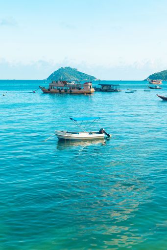 A vertical shot of boats on the water under a blue cloudy sky