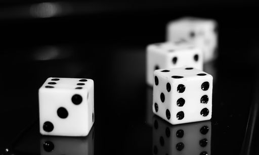 A closeup shot of several white dice on a black shiny surface with a blurry background
