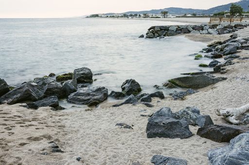 A closeup shot of the sea and sandy beach with stone