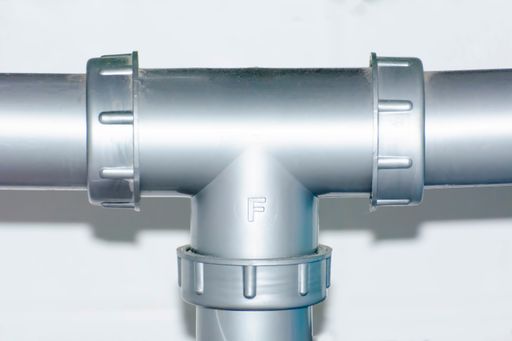 A closeup of a drainage pipe under a kitchen sink