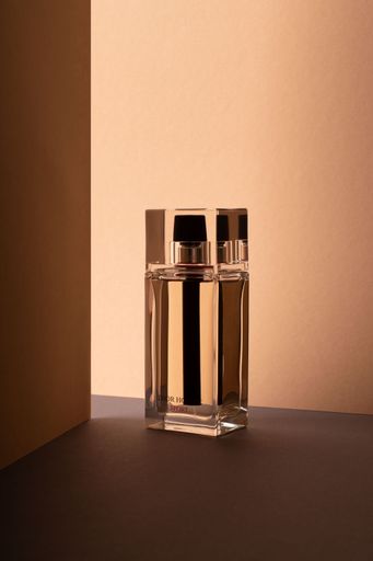 A Minimalist shot of a Dior Homme sport perfume bottle on a light pink background