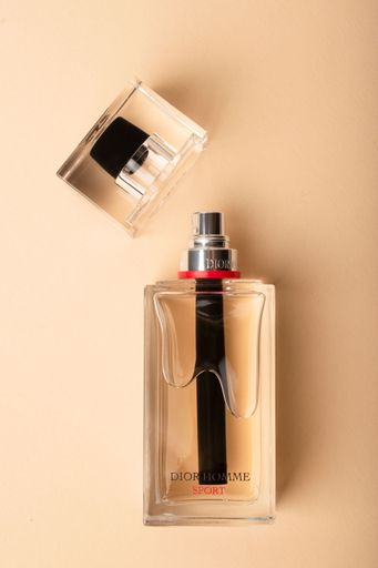A Minimalist shot of a Dior Homme sport perfume bottle on a light pink background