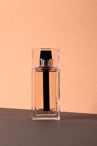 A Minimalist shot of a Dior Homme sport perfume bottle on a light pink background