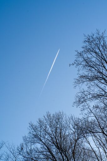A white trail of a flying airplane on a blue sky