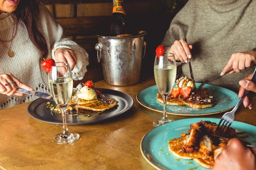 A top view of food and people's hands cutting their pancakes
