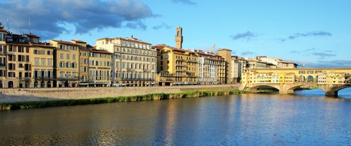 A scenic panoramic view of facades of riverside buildings and hotels near the Ponte Vecchio bridge in Florence, Italy