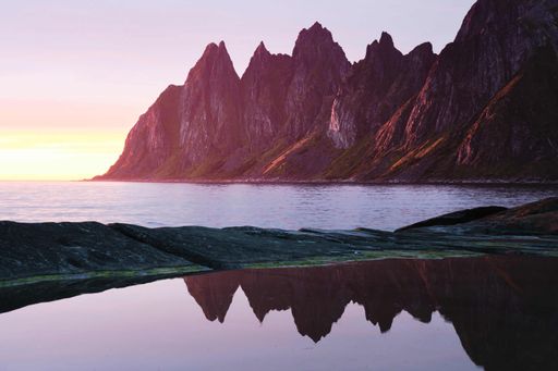 A beautiful scenery of rocky cliffs by the sea under a breathtaking cloudy sky at sunset