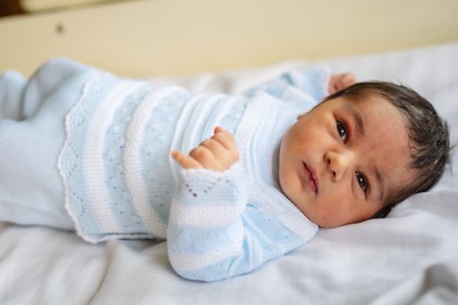 A photo of a newborn boy in the hospital, first day of life, opening his eyes for the first time