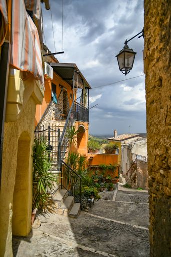 A vertical photo of a narrow street and classic buildings in Lavello, an old town in Basilicata region, Italy