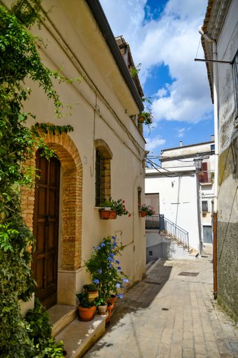 A vertical photo of a narrow street and classic buildings in Lavello, an old town in Basilicata region, Italy