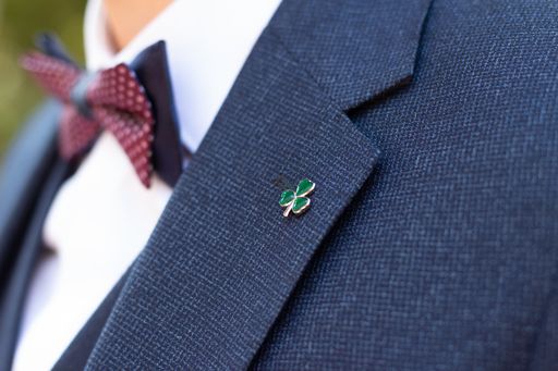 A closeup shot of a small three-leaf clover on the groom's suit