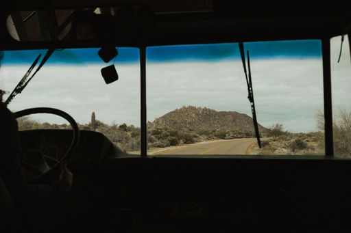 A panoramic shot of a road in a desert from inside a bus during daylight