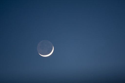 A beautiful shot of the sun behind the moon in a blue sky