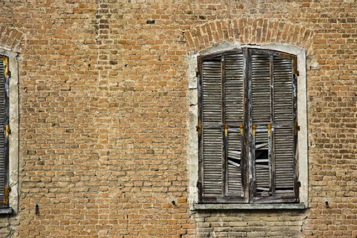 A beautiful shot of a brick house with a broken wooden window frame at daytime