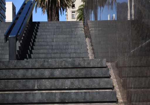 A closeup shot of a staircase outdoors with a marble wall on the side