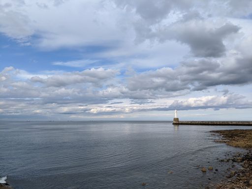 A beautiful shot of a calm sea with a lighthouse on the background