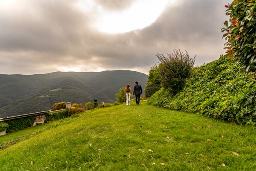 A landscape shot of a couple walking through a beautiful green meadow