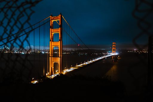 A high angle shot of the golden gate bridge under a dark blue sky at night time
