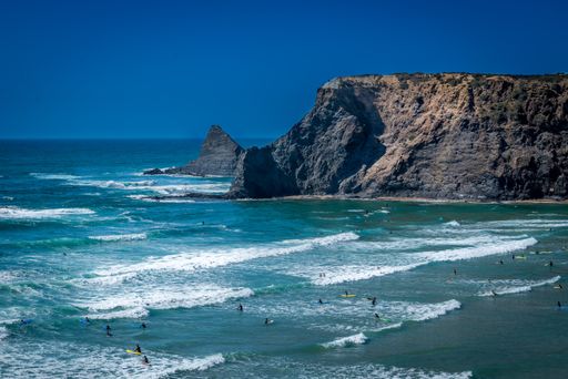 The wavy ocean hitting the rocky cliffs under the blue sky