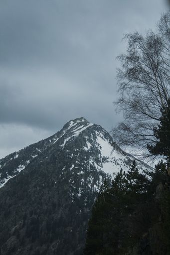 The snowy mountain peak in the Benasque town in Spain under the dark cloudy sky