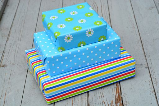 A closeup shot of three gift boxes in colorful wrapping stacked on top of each other on a wooden surface