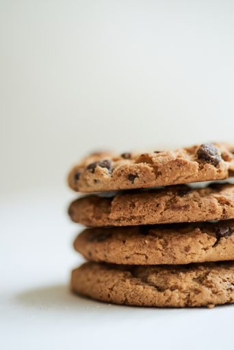 A vertical selective focus shot of chocolate chip cookies on a white surface