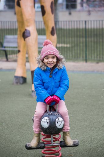 A selective focus shot of a portrait of a smiling girl playing in the park