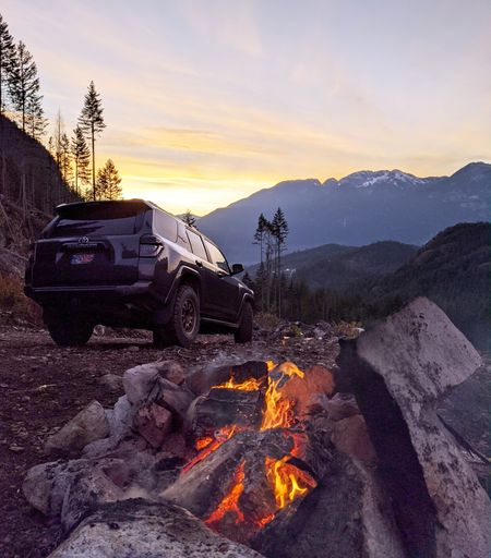 A vertical shot of a modern car parked near the bonfire