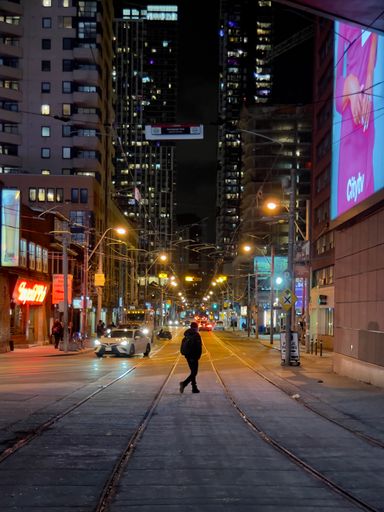 A vertical shot of a person walking in the streets of Toronto, Canada at night