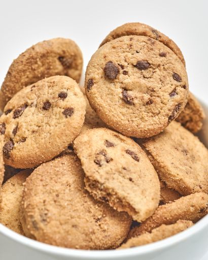 A vertical selective focus shot of chocolate chip cookies on a white surface