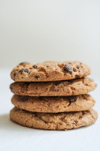 A vertical selective focus shot of chocolate chip cookies on a white surface