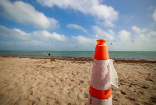 A sandy beach with a light orange traffic cone on the sand of Miami Key Biscayne, Crandon Park