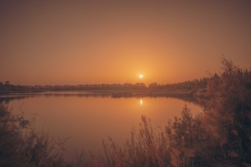 A breathtaking view of the sunset over a lake under a clear sky