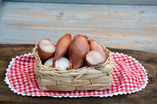 A closeup shot of sweet potatoes in a basket on a checkered red cloth on a wooden table