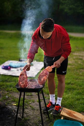 A vertical shot of a male doing a bbq of a Black Angus 3 pound bone-in ribeye