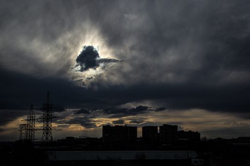 A breathtaking view of the dark cloudy sky at dawn over the silhouette of a cityscape