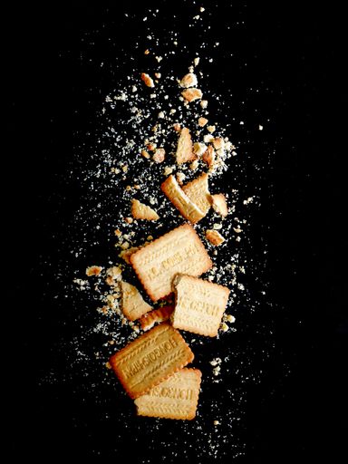 A vertical shot of crusty cookie and crumbs  on a black background
