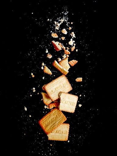 A vertical shot of crusty cookie and crumbs  on a black background