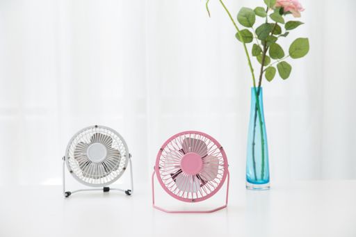 The small desk USB 4 blades cooling fans on a white table with roses in the background