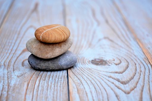 A shallow focus closeup shot of three pebbles stacked on top of each other on a wooden surface