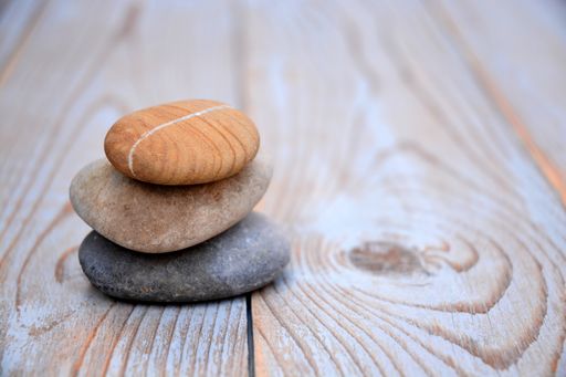 A shallow focus closeup shot of three pebbles stacked on top of each other on a wooden surface