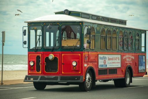 A red public bus with an ocean in the background