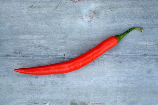 A high angle closeup shot of a red hot chili pepper on a wooden surface