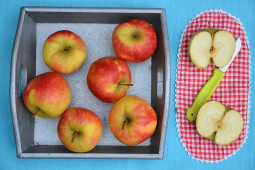 A high angle shot of red and yellow apples in a tray and cut in a checkered red plate