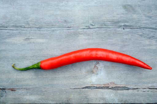 A high angle closeup shot of a red hot chili pepper on a wooden surface