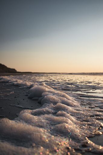 A vertical shot of a beautiful sea captured from a rocky shore during a mesmerizing sunset