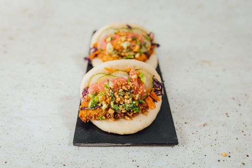 A closeup shot of a steamed bao bun with meat and vegetables