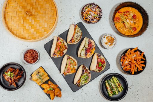 A top view of bao buns surrounded by different dishes on a white table